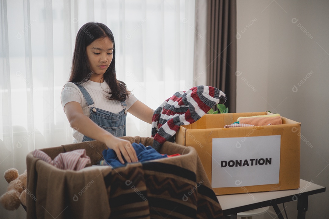 Linda garota sorridente segurando roupas e brinquedos para doação