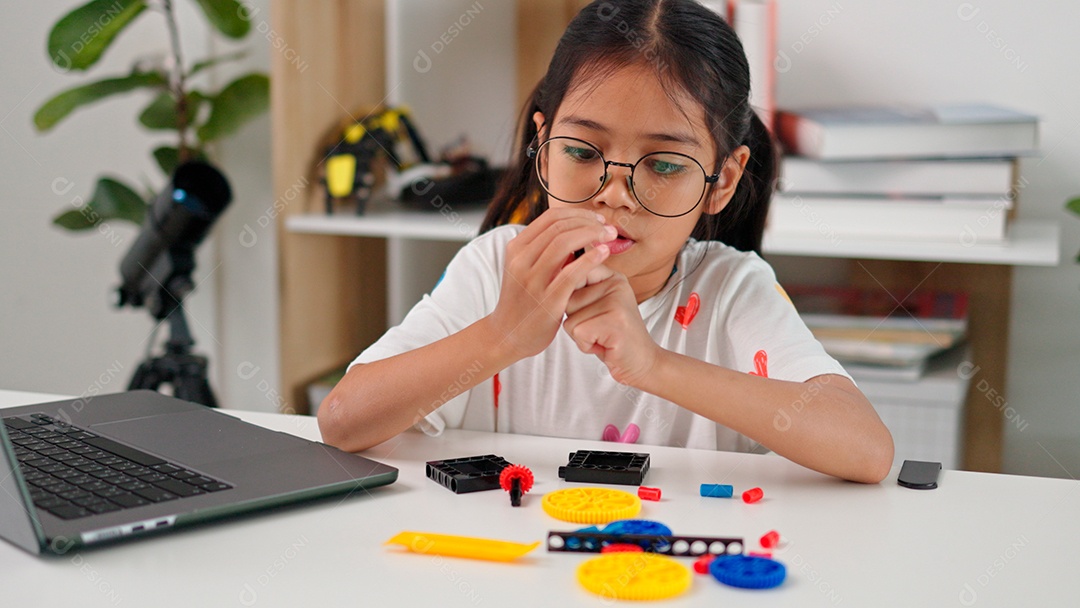 Linda garota de óculos apontando lápis e mechendo em leptop sobre mesa de madeira