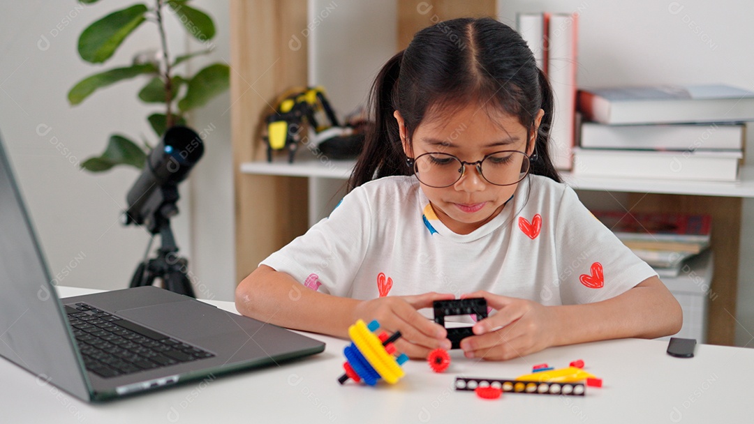 Linda criança brincando ao lado de leptop sobre fundo de um quarto