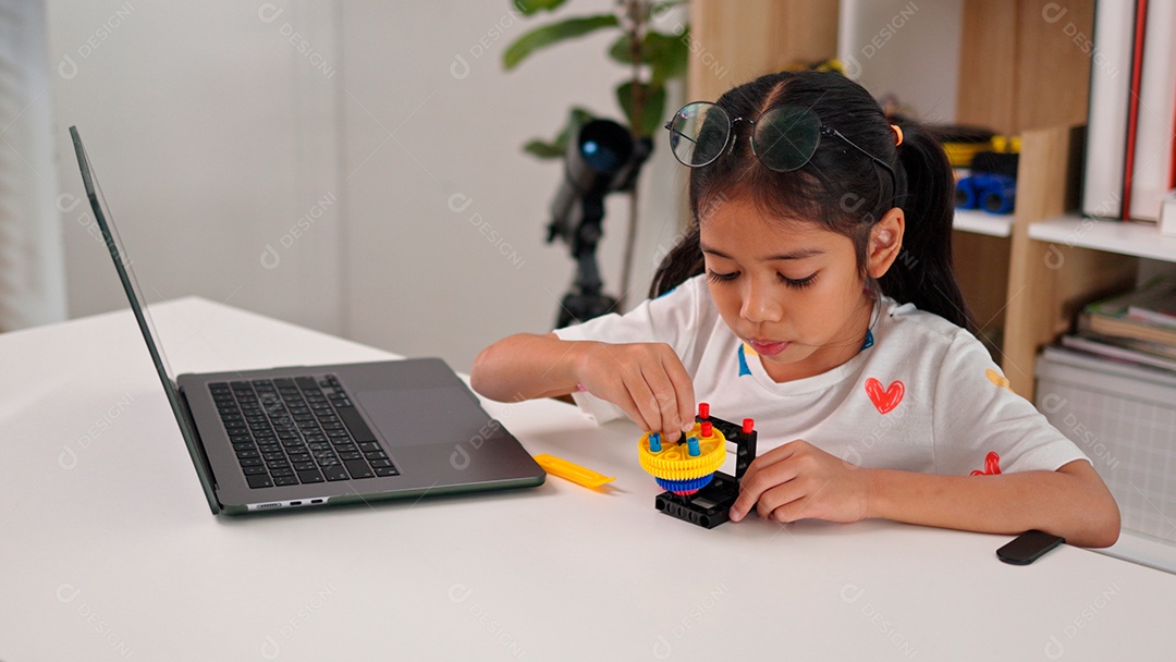Linda criança brincando ao lado de leptop sobre fundo de um quarto