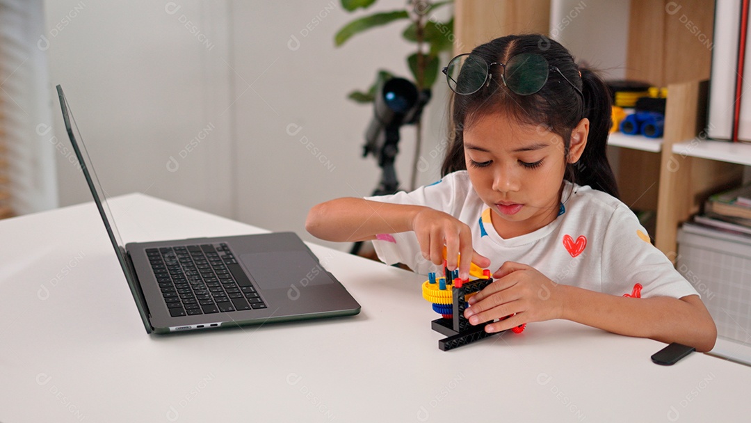 Linda criança brincando ao lado de leptop sobre fundo de um quarto