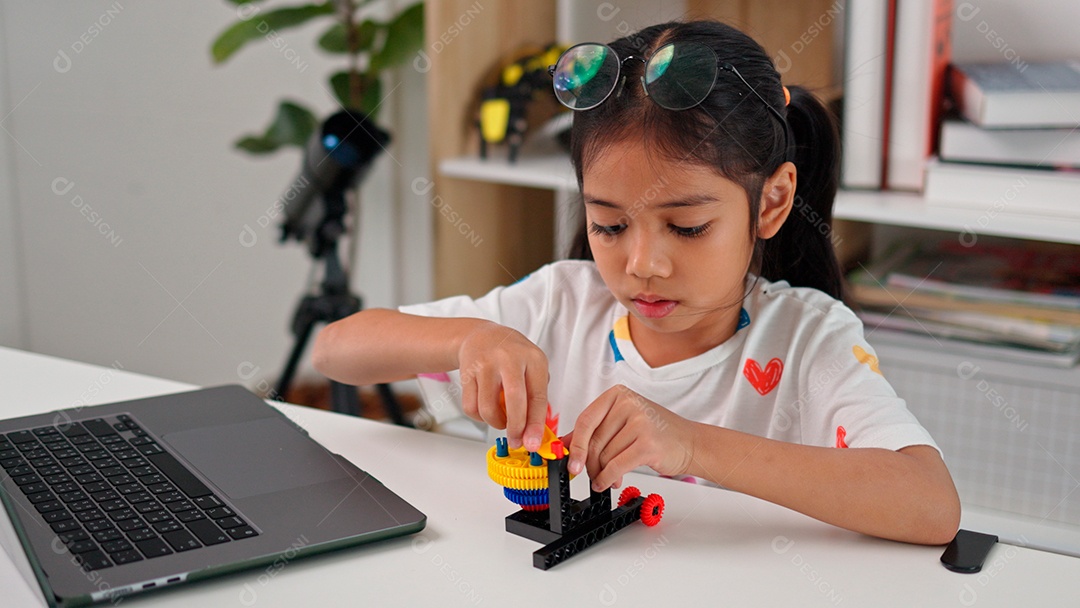 Linda criança brincando ao lado de leptop sobre fundo de um quarto