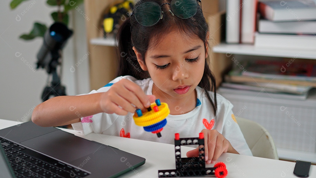 Linda criança brincando ao lado de leptop sobre fundo de um quarto