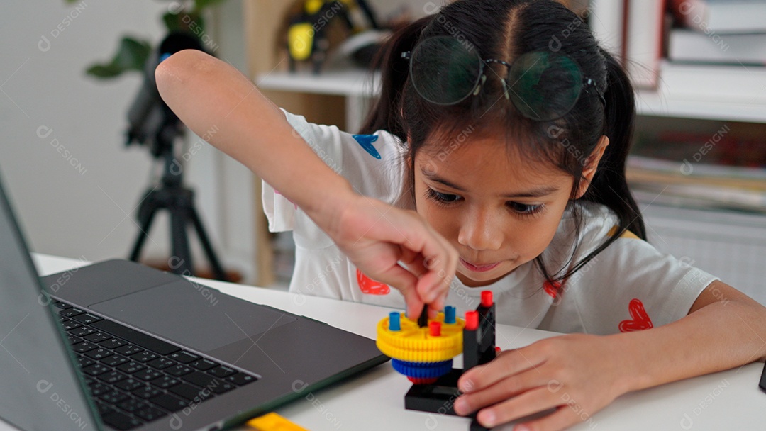 Linda criança brincando ao lado de leptop sobre fundo de um quarto