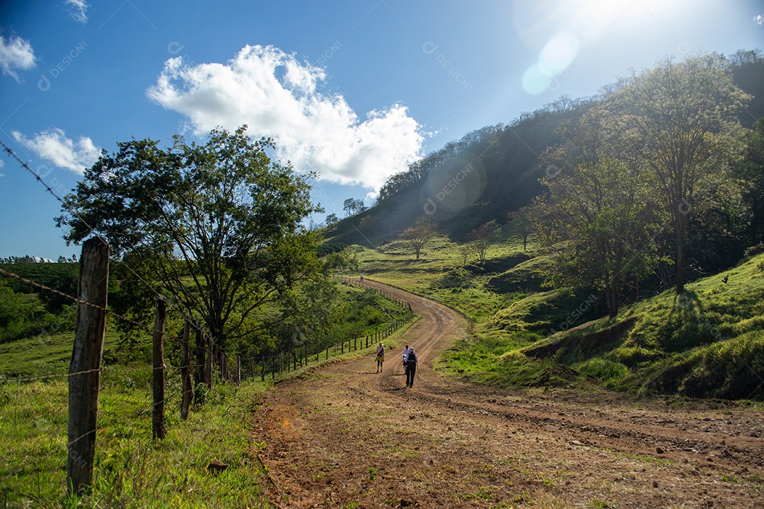 Estrada de chão com pessoas caminhando uma linda paisagem verdes