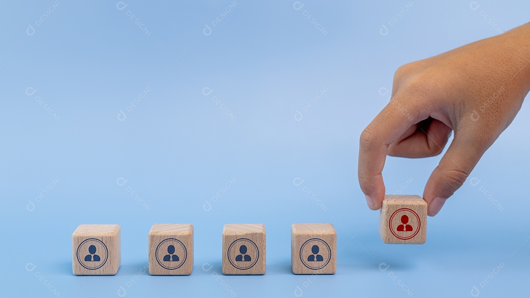 Mão de empresário empilhando cubo de madeira sobre fundo azul desfocado