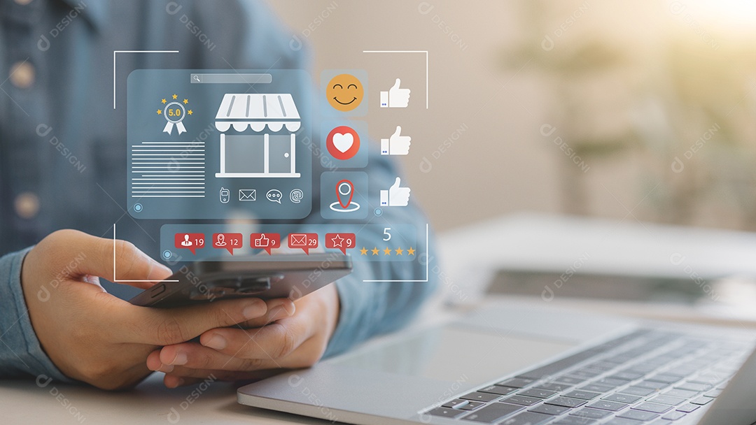 Mão de empresário mechendo em smartphone ao lado de um leptop sobre fundo desfocado