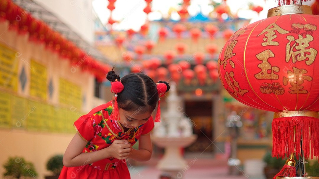 Linda menina asiática feliz vestindo uma decoração de cheongsam tradicional chinesa vermelha sobre fundo desfocado