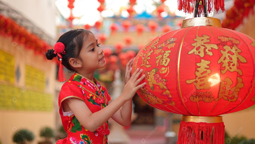 Linda menina asiática feliz vestindo uma decoração de cheongsam tradicional chinesa vermelha sobre fundo desfocado