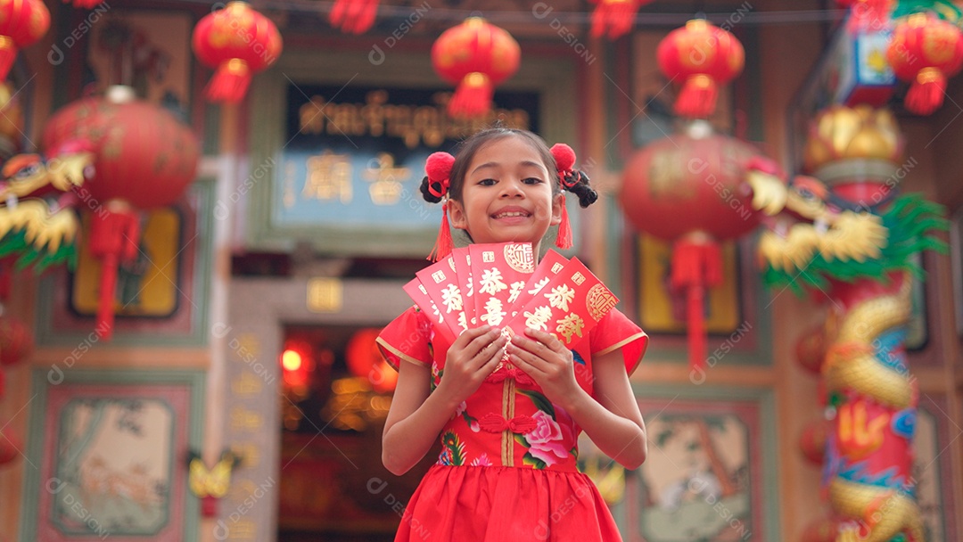 Linda menina asiática feliz vestindo uma decoração de cheongsam tradicional chinesa vermelha sobre fundo desfocado