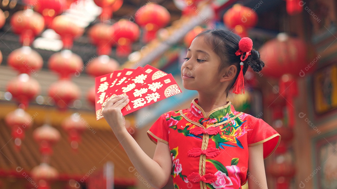 Linda menina asiática feliz vestindo uma decoração de cheongsam tradicional chinesa vermelha sobre fundo desfocado