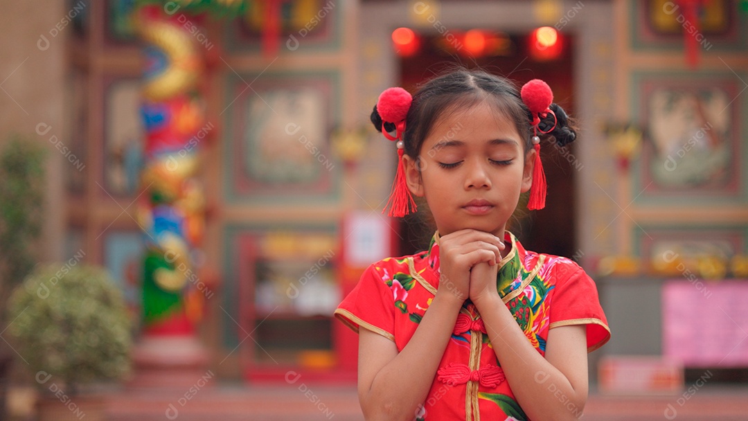Linda menina asiática feliz vestindo uma decoração de cheongsam tradicional chinesa vermelha sobre fundo desfocado