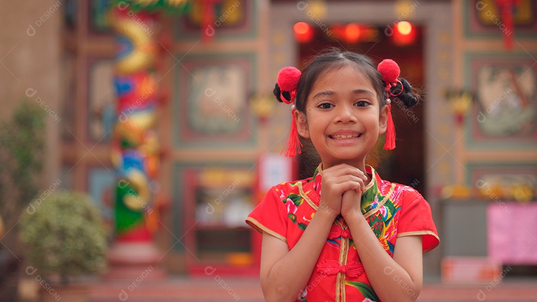 Linda menina asiática feliz vestindo uma decoração de cheongsam tradicional chinesa vermelha sobre fundo desfocado