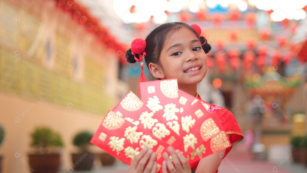 Linda menina asiática feliz vestindo uma decoração de cheongsam tradicional chinesa vermelha sobre fundo desfocado