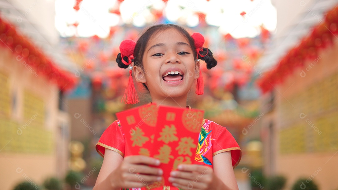 Linda menina asiática feliz vestindo uma decoração de cheongsam tradicional chinesa vermelha sobre fundo desfocado