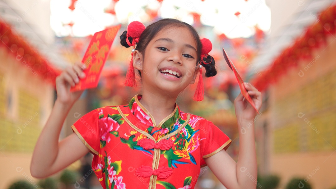 Linda menina asiática feliz vestindo uma decoração de cheongsam tradicional chinesa vermelha sobre fundo desfocado