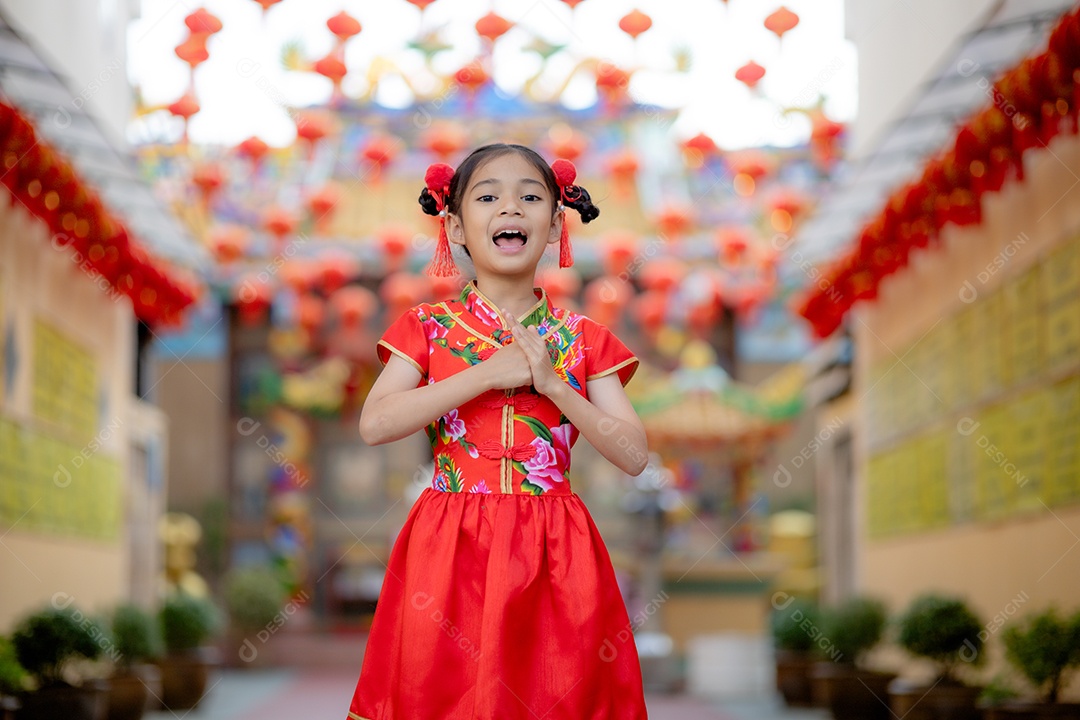 Linda menina asiática feliz vestindo uma decoração de cheongsam tradicional chinesa vermelha sobre fundo desfocado
