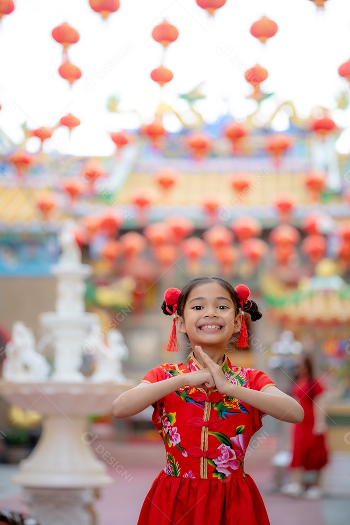 Linda menina asiática feliz vestindo uma decoração de cheongsam tradicional chinesa vermelha sobre fundo desfocado