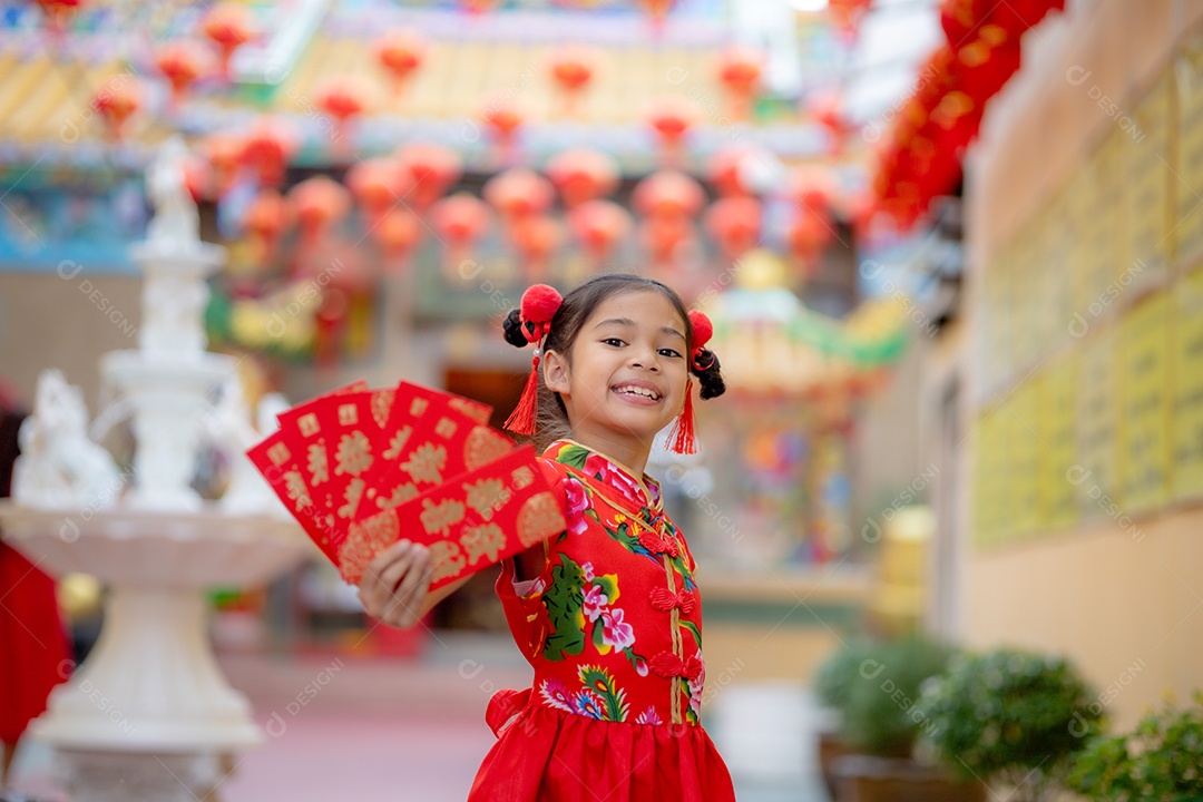 Linda menina asiática feliz vestindo uma decoração de cheongsam tradicional chinesa vermelha sobre fundo desfocado