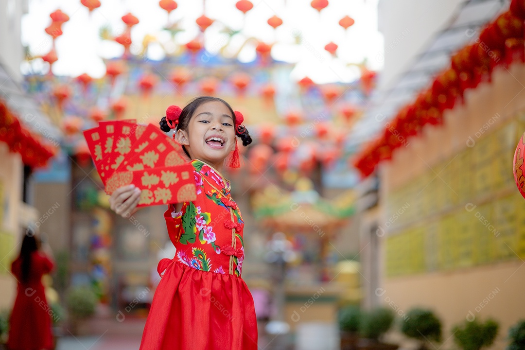 Linda menina asiática feliz vestindo uma decoração de cheongsam tradicional chinesa vermelha sobre fundo desfocado
