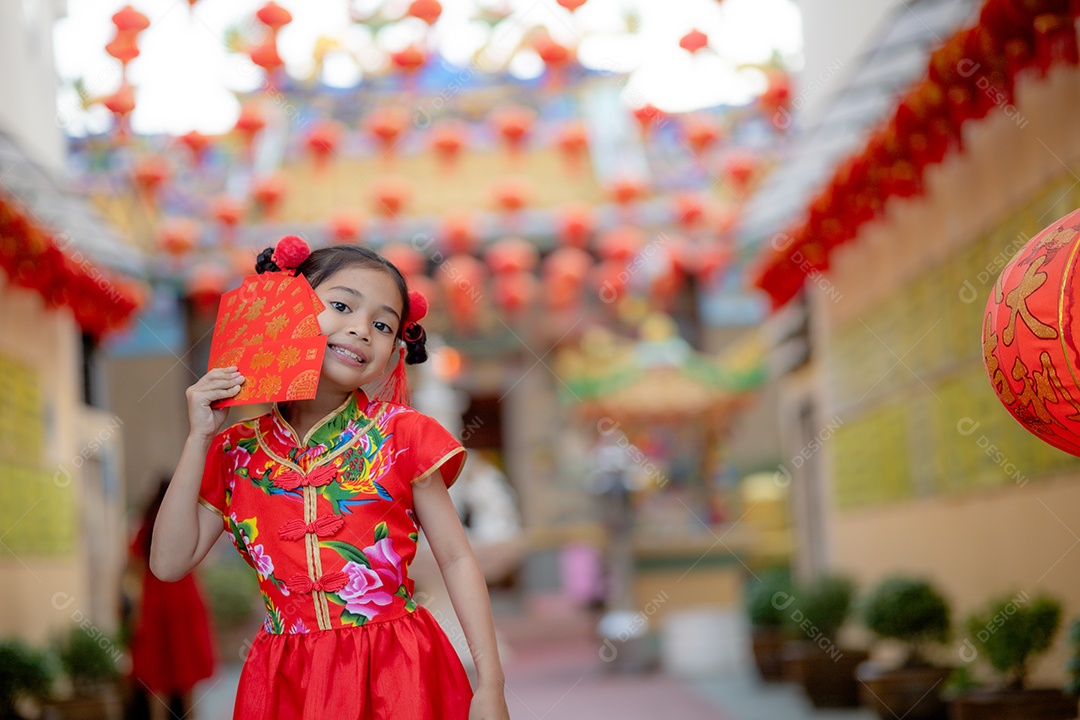 Linda menina asiática feliz vestindo uma decoração de cheongsam tradicional chinesa vermelha sobre fundo desfocado