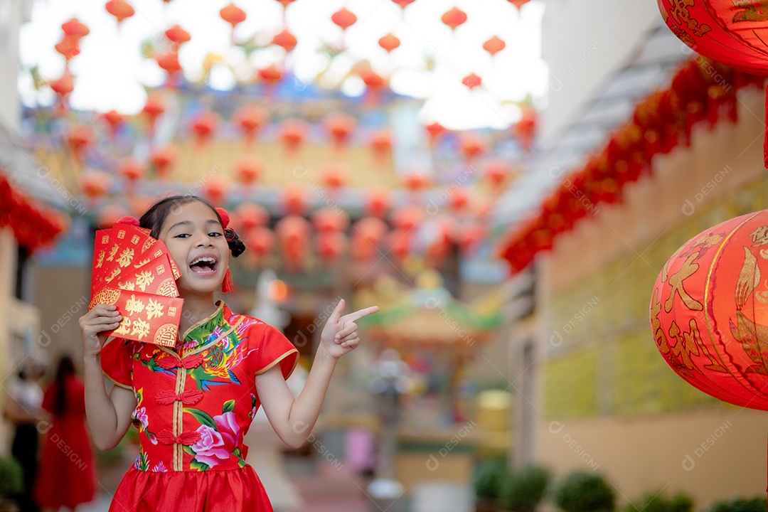 Linda menina asiática feliz vestindo uma decoração de cheongsam tradicional chinesa vermelha sobre fundo desfocado