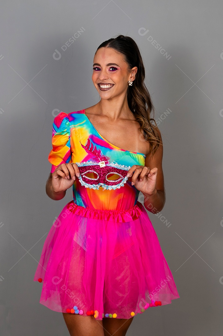 Linda mulher sorridente fantasiada segurando máscara sobre fundo isolado