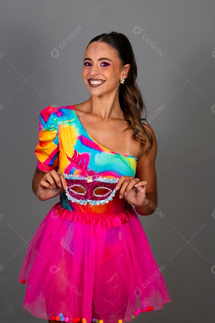 Linda mulher sorridente fantasiada segurando máscara sobre fundo isolado