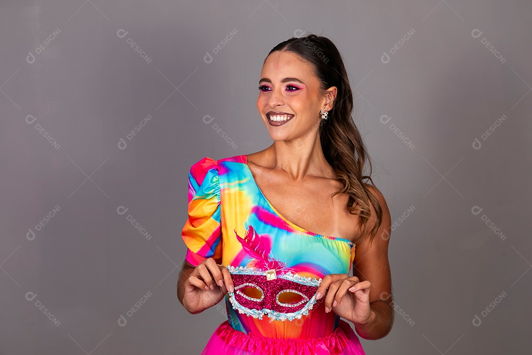 Linda mulher sorridente fantasiada segurando máscara sobre fundo isolado