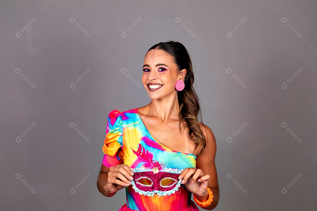 Linda mulher sorridente fantasiada segurando máscara sobre fundo isolado