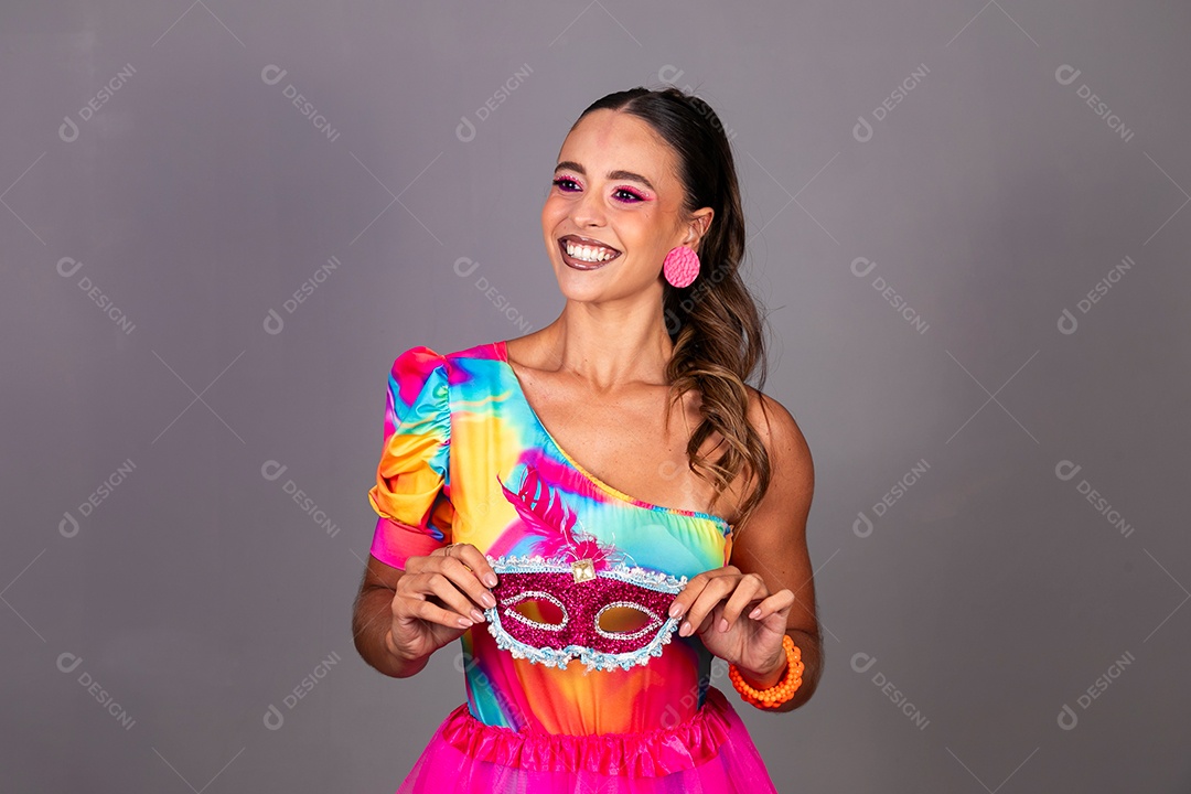 Linda mulher sorridente fantasiada segurando máscara sobre fundo isolado