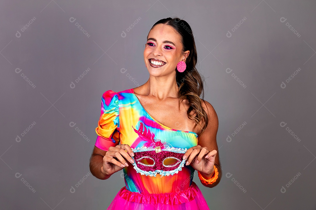 Linda mulher sorridente fantasiada segurando máscara sobre fundo isolado