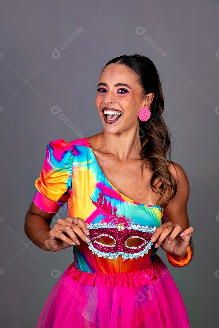 Linda mulher sorridente fantasiada segurando máscara sobre fundo isolado