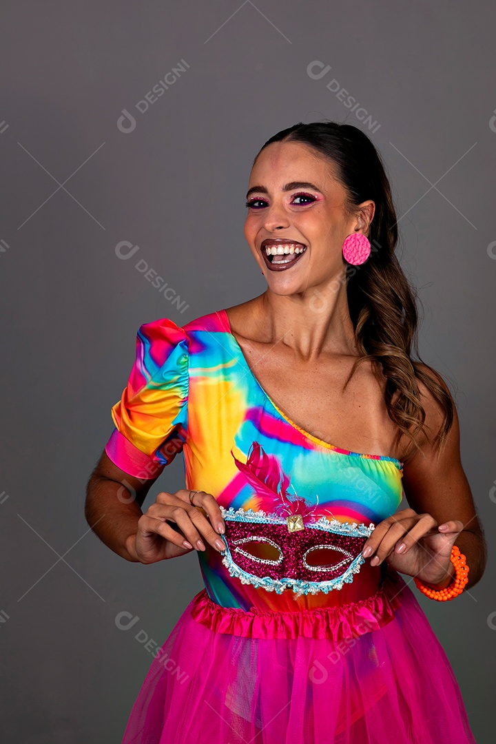 Linda mulher sorridente fantasiada segurando máscara sobre fundo isolado