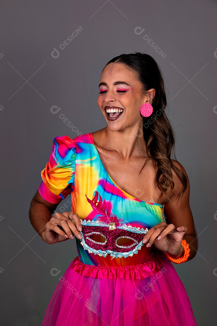 Linda mulher sorridente fantasiada segurando máscara sobre fundo isolado