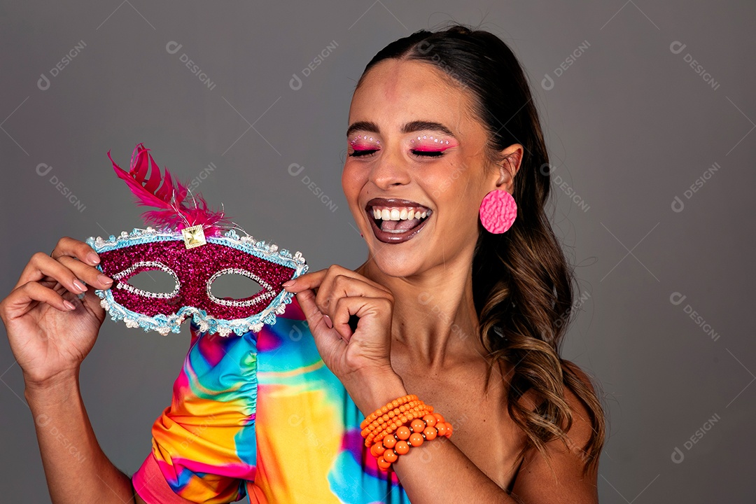 Linda mulher sorridente fantasiada segurando máscara sobre fundo isolado