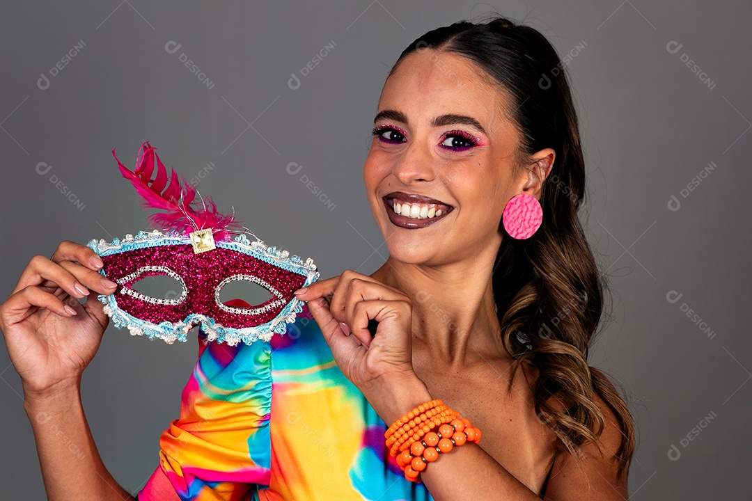 Linda mulher sorridente fantasiada segurando máscara sobre fundo isolado