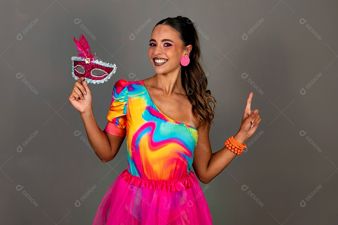 Linda mulher sorridente fantasiada segurando máscara sobre fundo isolado