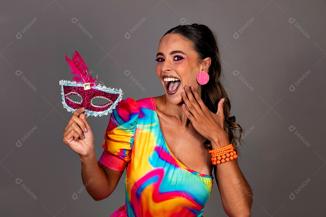 Linda mulher sorridente fantasiada segurando máscara sobre fundo isolado