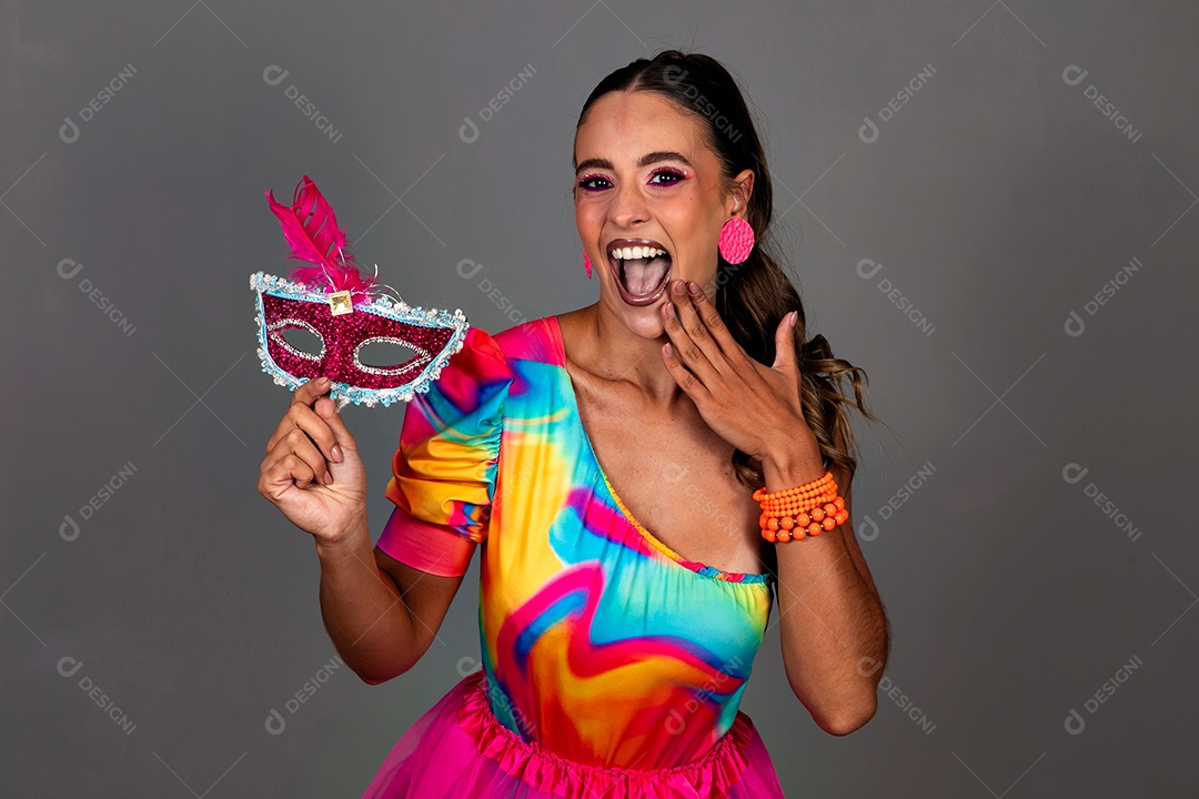 Linda mulher sorridente fantasiada segurando máscara sobre fundo isolado