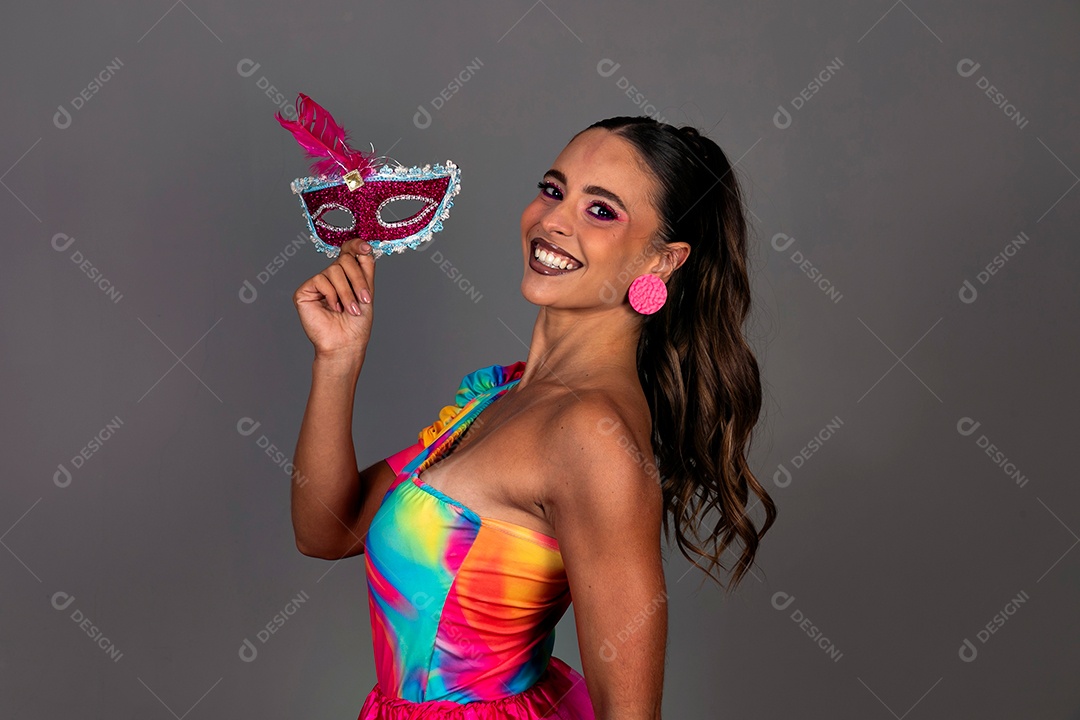 Linda mulher sorridente fantasiada segurando máscara sobre fundo isolado