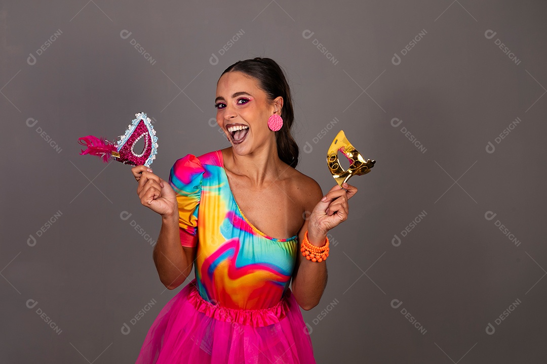 Linda mulher sorridente fantasiada segurando máscara sobre fundo isolado