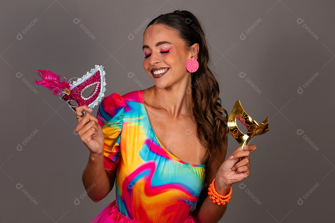 Linda mulher sorridente fantasiada segurando máscara sobre fundo isolado