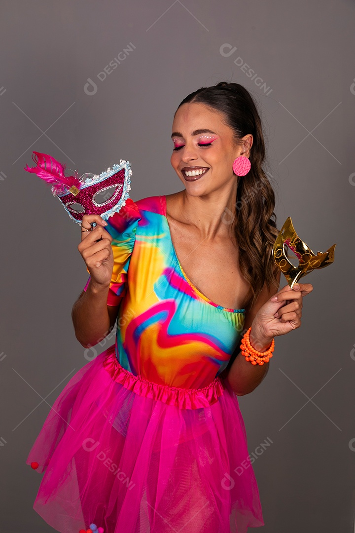 Linda mulher sorridente fantasiada segurando máscara sobre fundo isolado