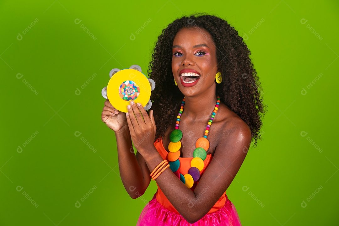 Linda morena do cabelo cacheado sorridente fantasiada segurando pandeiro sobre fundo verde isolado