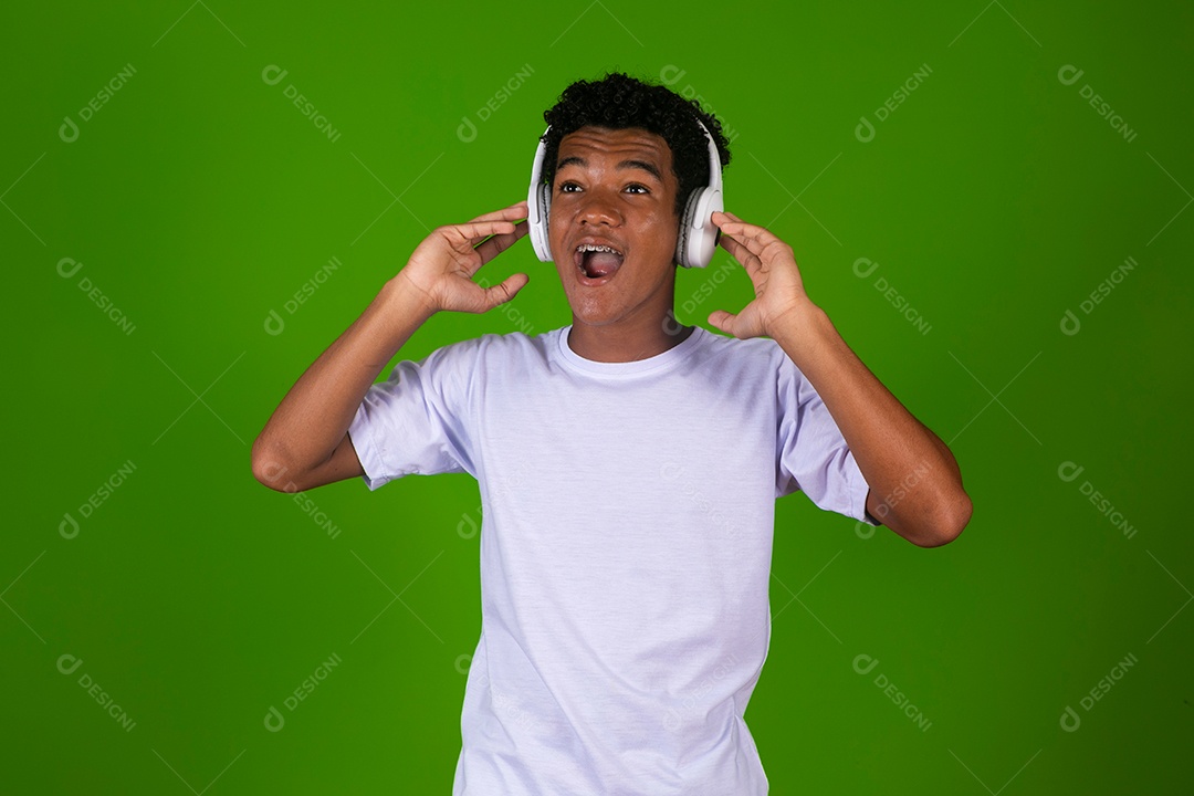 Lindo garoto negro de camisa branca usando fone de ouvido sobre fundo verde isolado