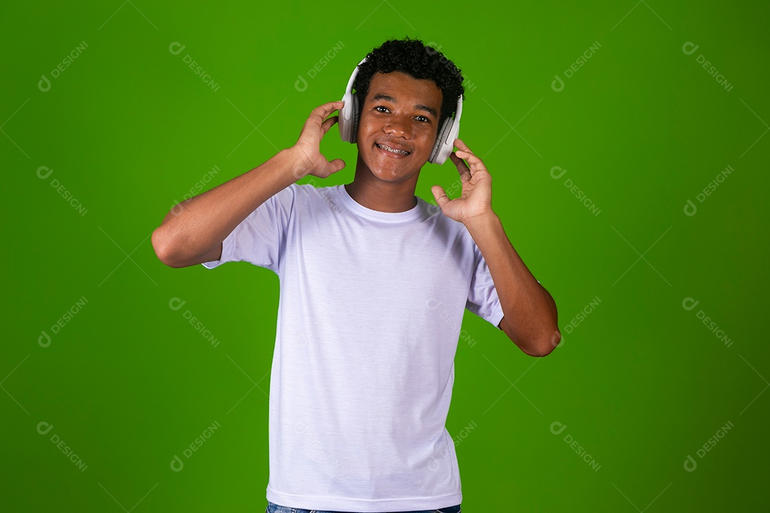 Lindo garoto negro de camisa branca usando fone de ouvido sobre fundo verde isolado