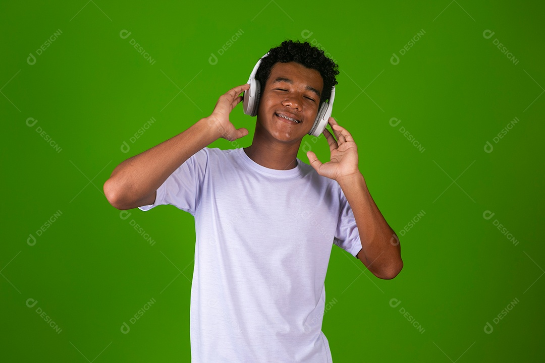 Lindo garoto negro de camisa branca usando fone de ouvido sobre fundo verde isolado