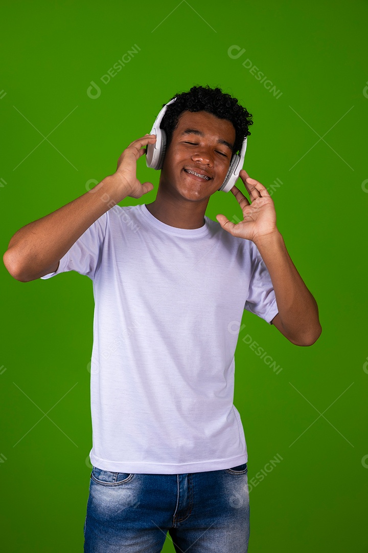 Lindo garoto negro de camisa branca usando fone de ouvido sobre fundo verde isolado