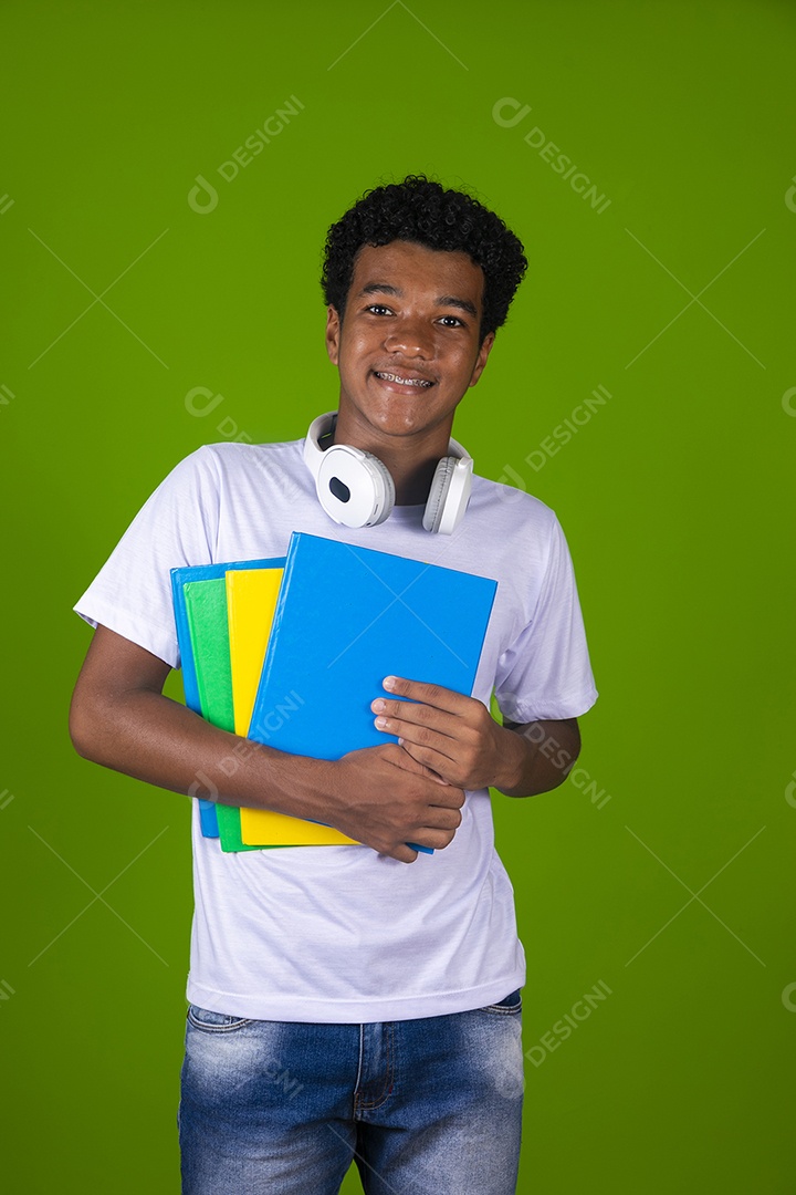 Um jovem com livros nas mãos e um fone no pescoço